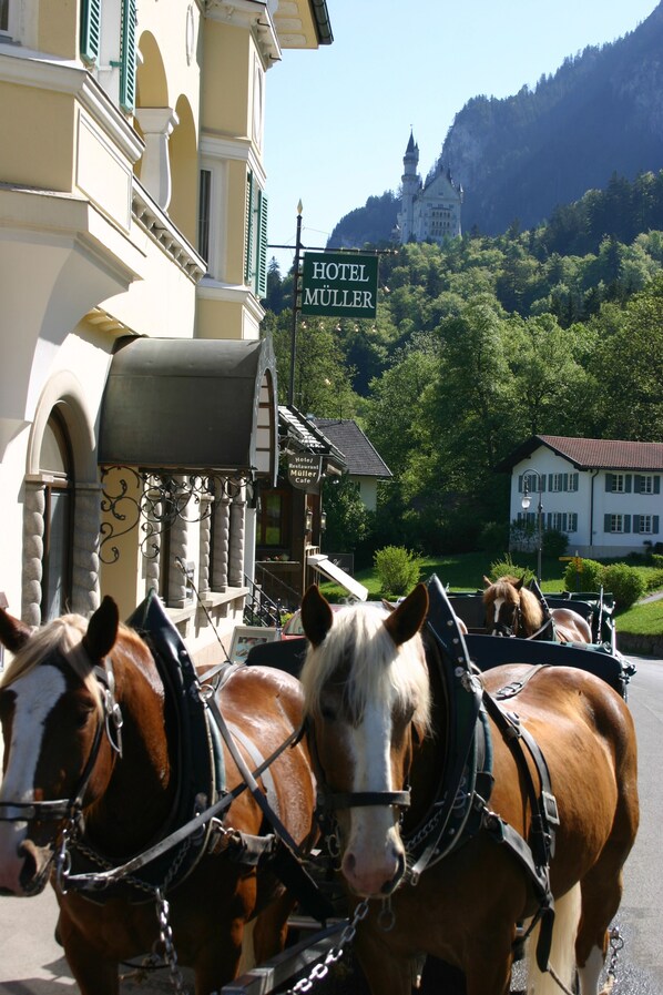 A horse-drawn carriage in front of a building with a sign that reads "Hotel Müller." - Hotel Müller Hohenschwangau (Schwangau)