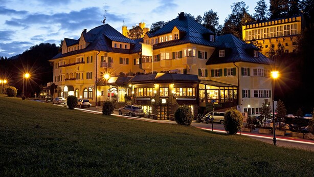 Een groot, meerlaags hotel in klassieke Europese stijl, met балконы en een goed verlichte gevel.