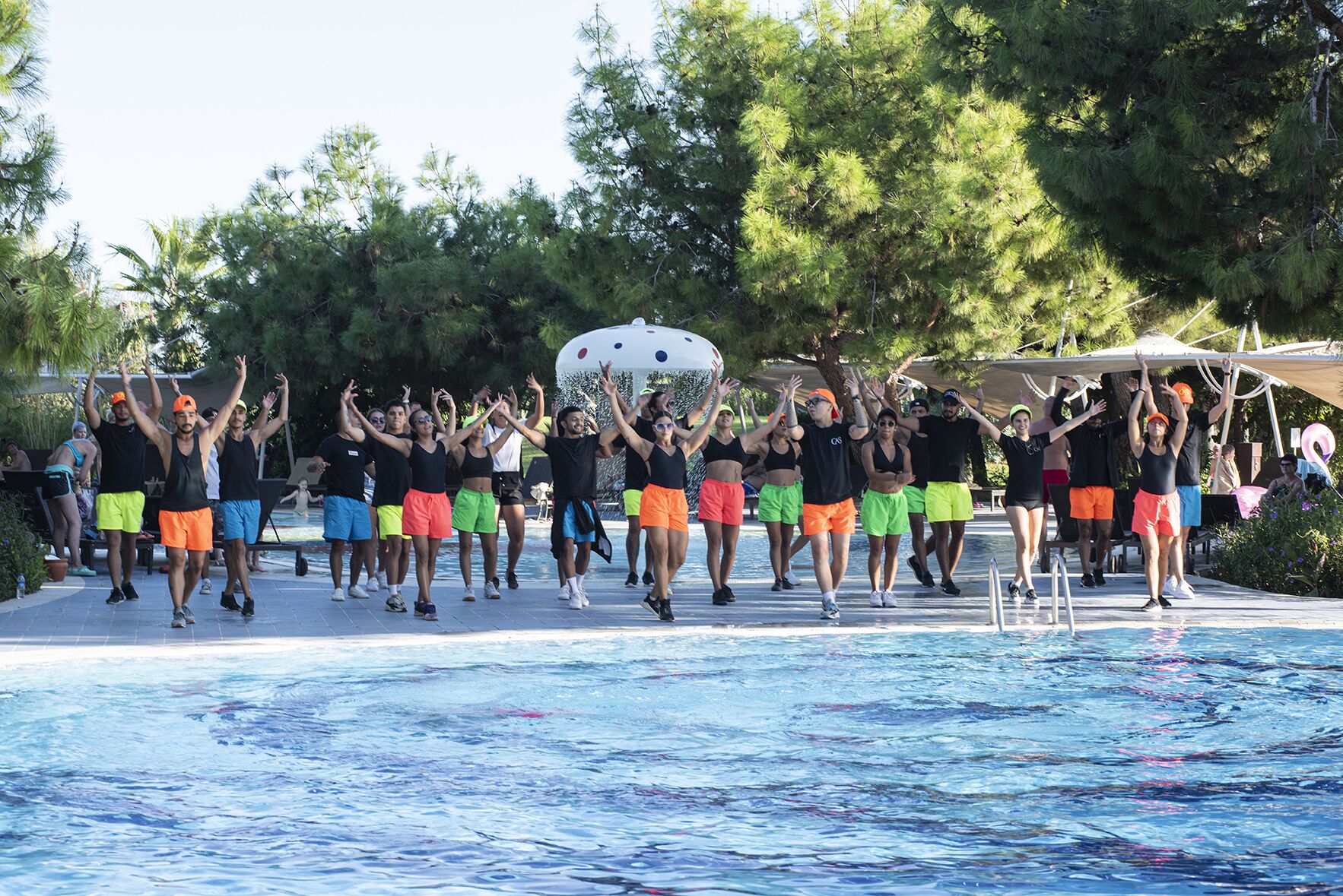 Un grupo de personas realizando una rutina de ejercicios sincronizados junto a una piscina.