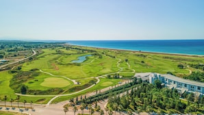 Un parcours de golf offrant une vue sur l’océan, un espace de stationnement et un bâtiment au design moderne.