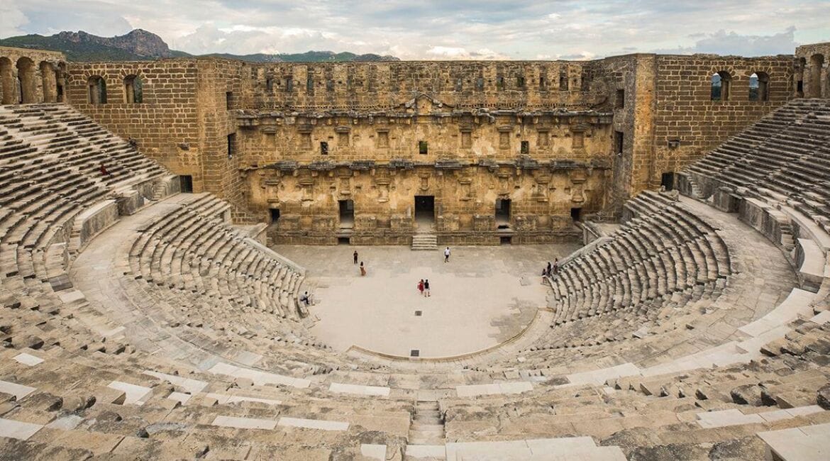 An ancient amphitheater with stone seating and a central stage.