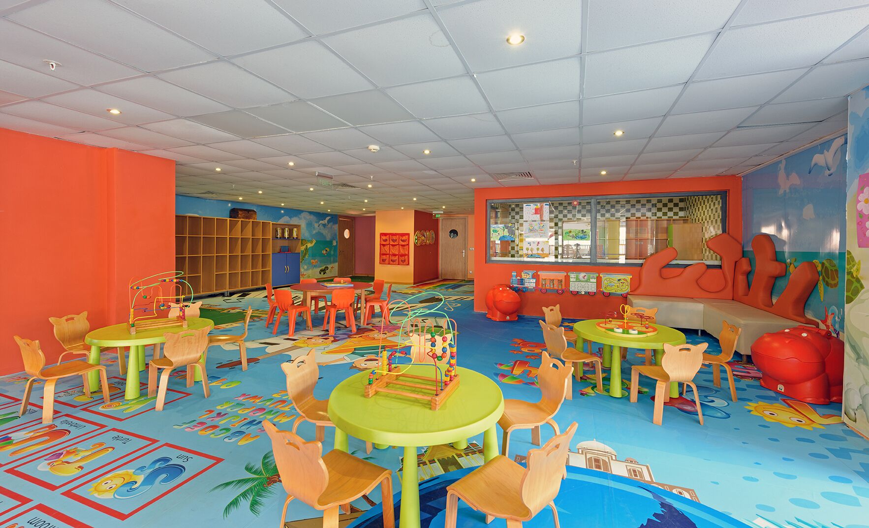 Una sala de juegos para niños con paredes, mesas y sillas coloridas.