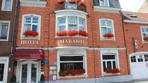 A hotel with a red brick facade, white-framed windows, and flower boxes on the second floor. - Hotel Maraboe (Bruges)