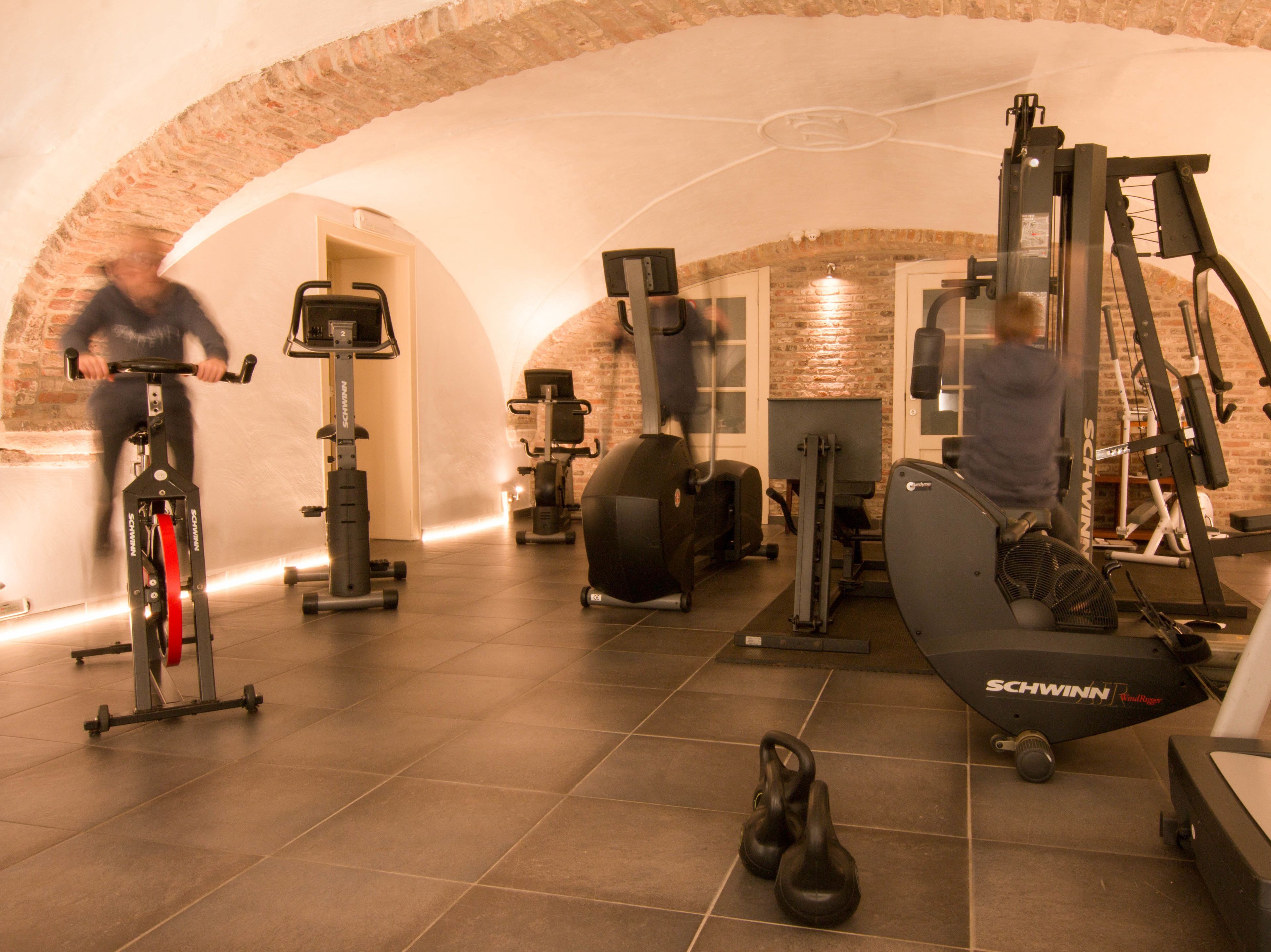 Uma academia com diversos equipamentos de exercício, incluindo bicicleta ergométrica, elíptico e aparelhos de musculação.
