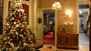 A Christmas tree in a hotel lobby with a dining area in the background. - Hotel Maraboe (Bruges)