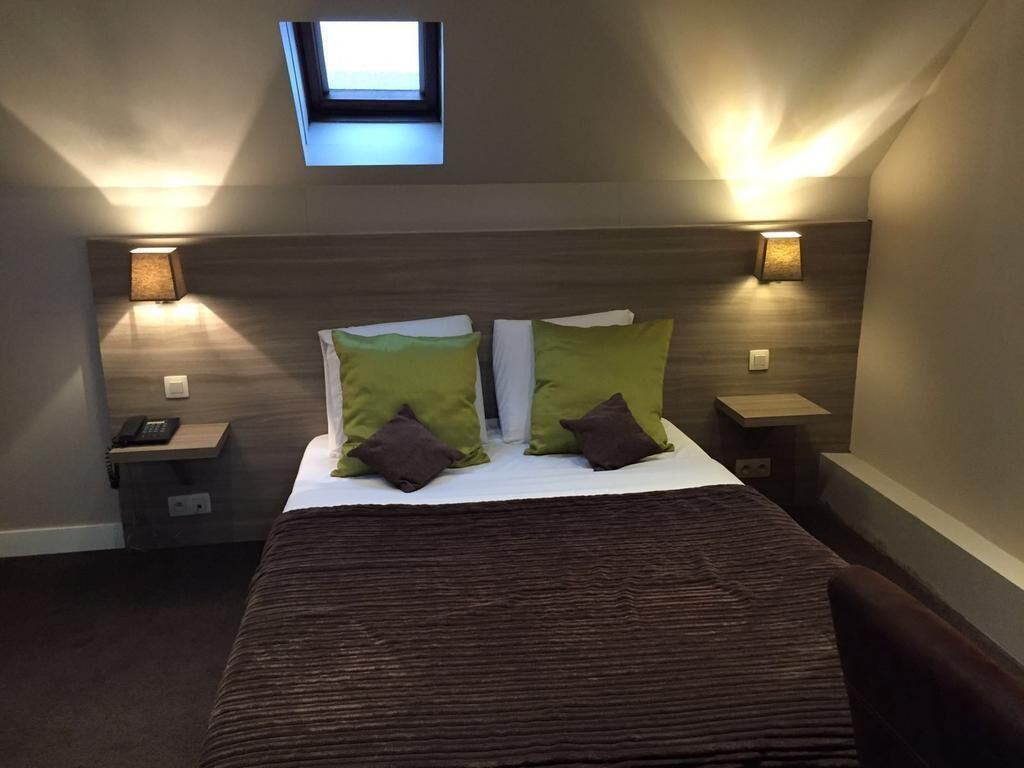 A bedroom with a bed, two bedside tables, a nightstand, a window, and wall-mounted lamps.