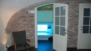 An arched brick corridor leading to a room with a bed and a chair. - Hotel Maraboe (Bruges)