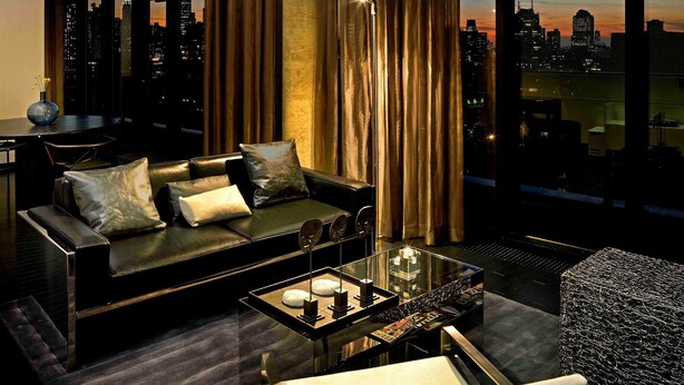 Ein modernes Wohnzimmer mit großem Fenster, einer schwarzen Ledersofa, einem Glastisch und einer dekorativen Chandel.
