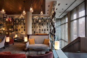 A modern lobby with a sofa, armchairs, and a staircase.