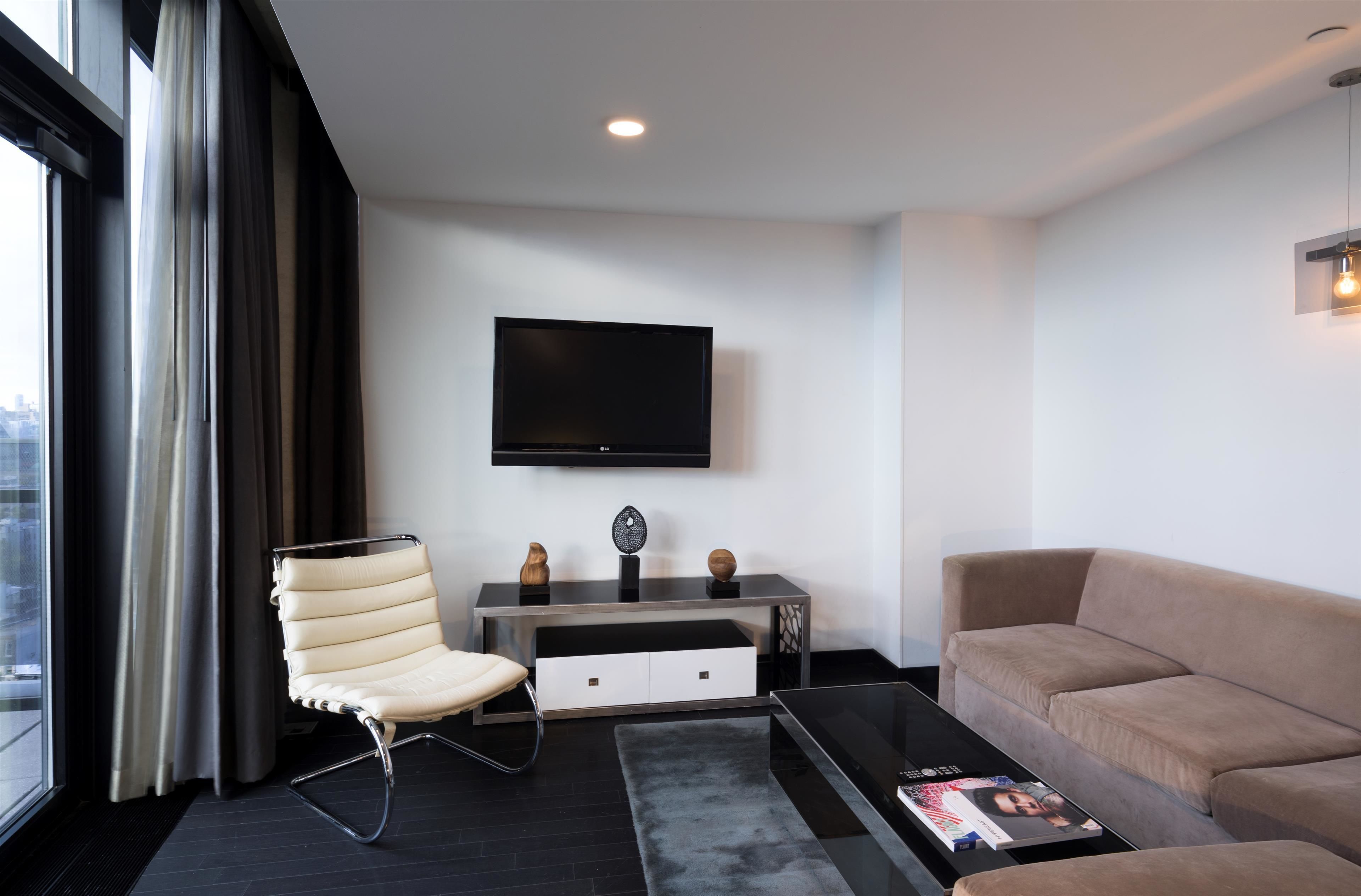 A modern living room with a sofa, a chair, a coffee table, a TV, and a console table with decorative items.