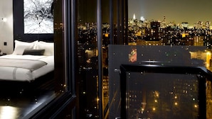 Ein modernes Schlafzimmer mit Stadtblick, ein Balkon mit Weitblick über die Stadt und ein großes Fenster.