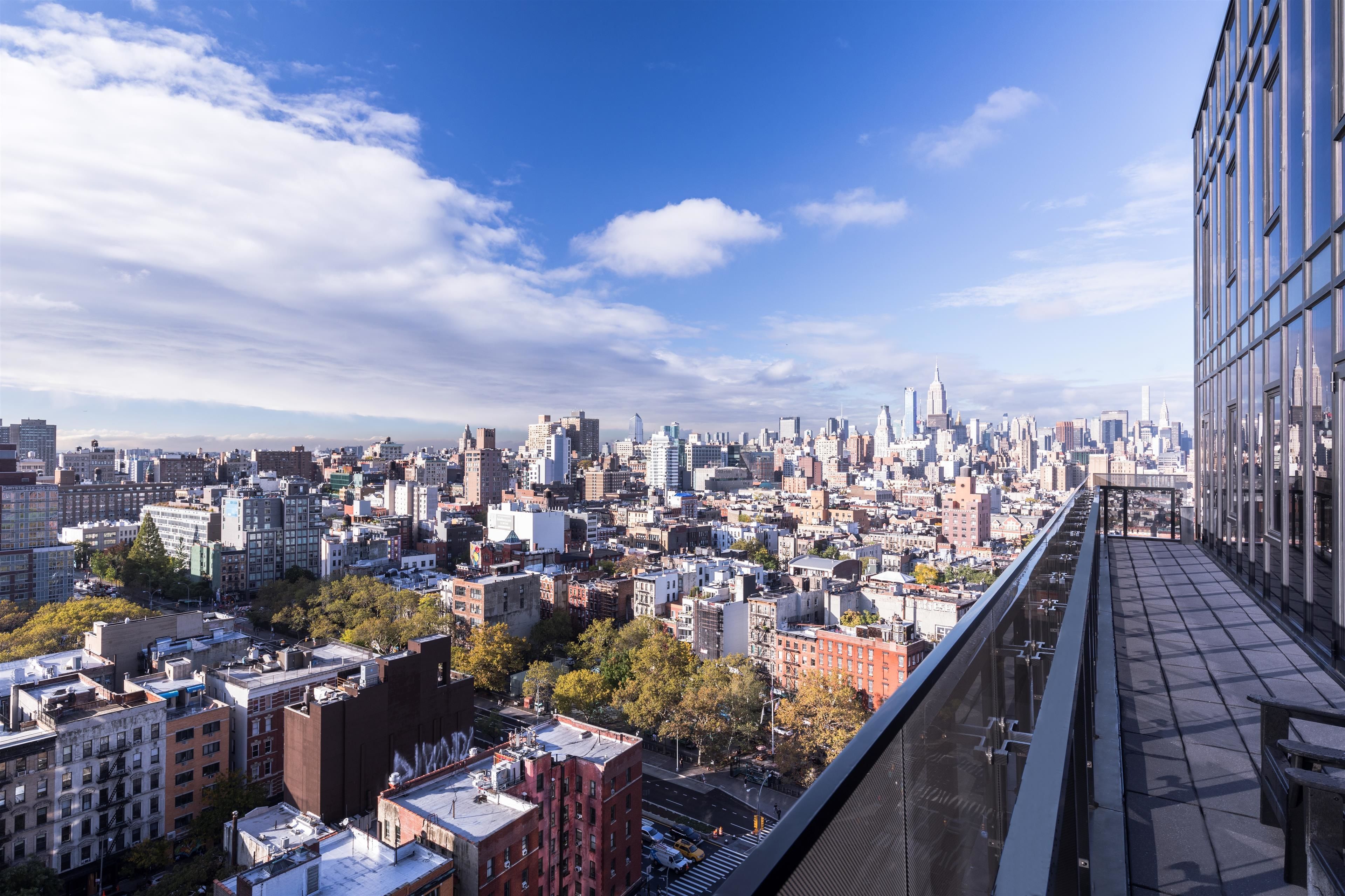 A cityscape with a high-rise building featuring a glass facade and a pedestrian bridge.