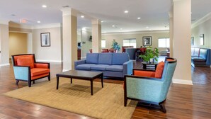 A spacious living area with a blue sofa, orange armchairs, and a coffee table. - Comfort Inn Huntsville Research Park (Huntsville)