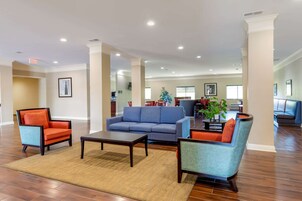 A spacious living area with a blue sofa, orange armchairs, and a coffee table.