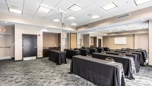 A conference room with multiple tables, carpeted flooring, and ceiling lights.