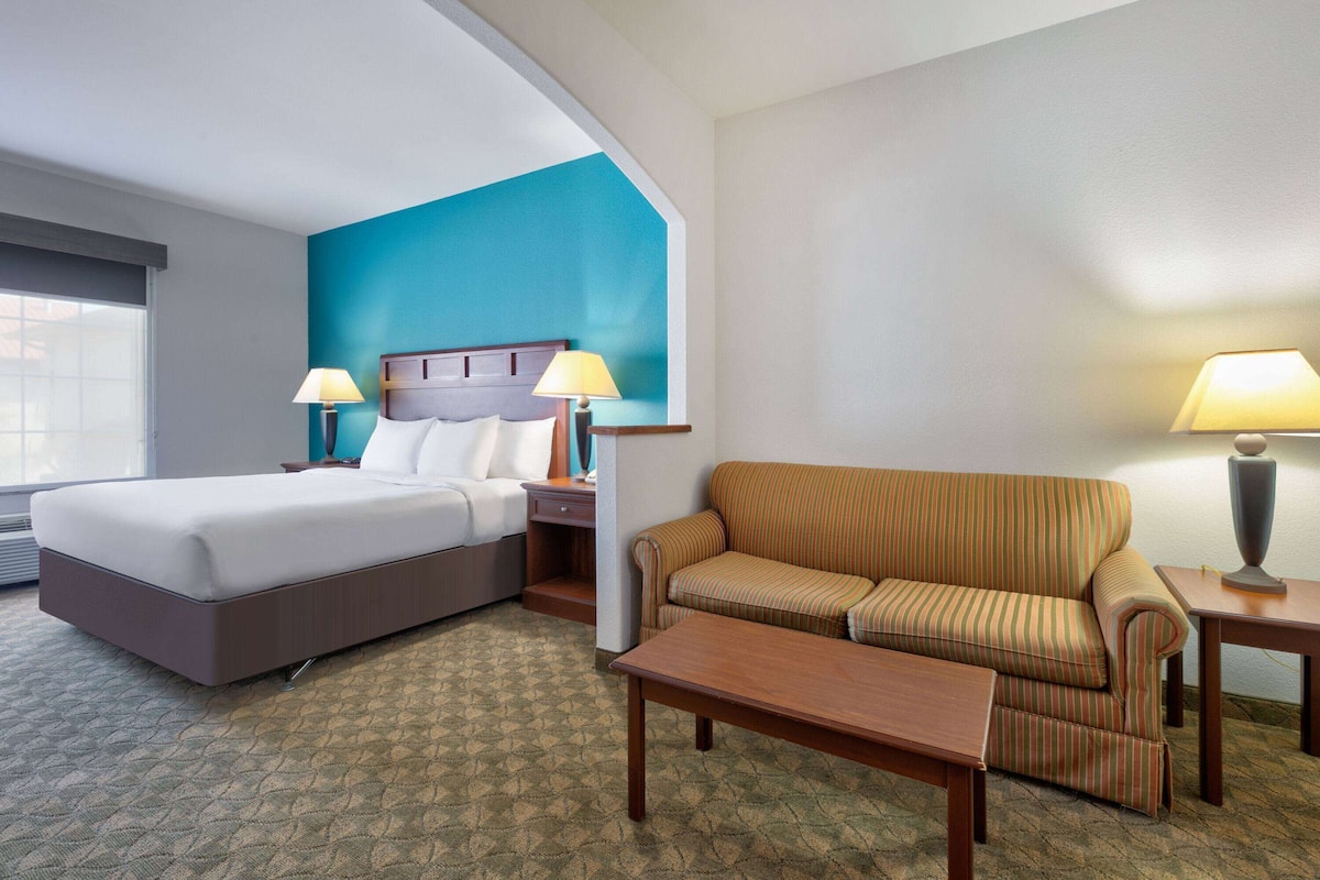 Una habitación de hotel con una cama, un sofá, una mesita de centro y dos lámparas.