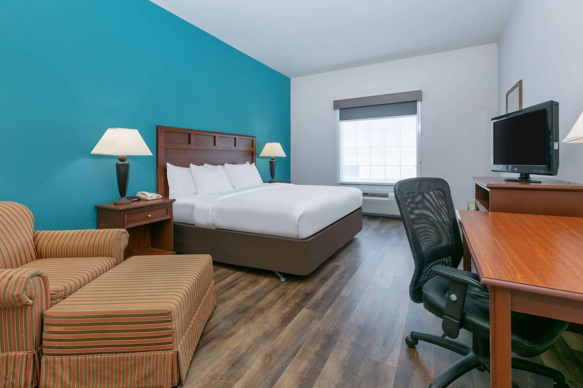 Una habitación de hotel con cama, escritorio, silla, televisión y ventana.