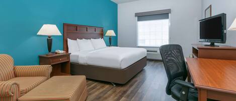 A hotel room with a bed, a desk, a chair, a TV, and a window.