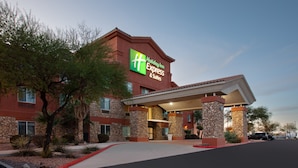 A Holiday Inn Express & Suites building with a stone facade, a covered entrance, and a parking lot.