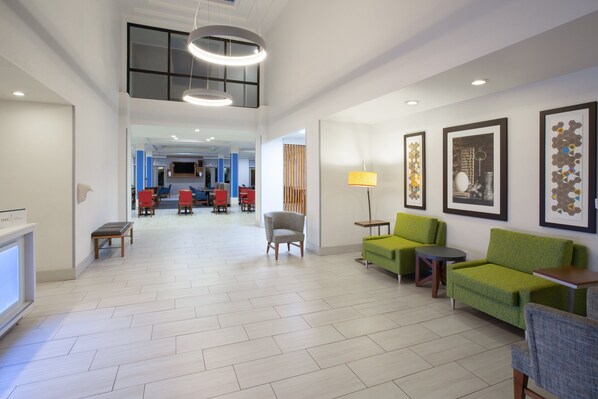 A spacious lobby with a high ceiling, modern furniture, and artwork on the walls. - Holiday Inn Express & Suites Tucson by IHG (Tucson)