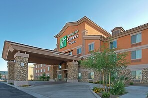 Un hotel Holiday Inn Express con fachada de piedra, múltiples ventanales y una entrada cubierta.