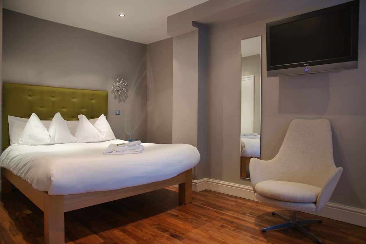 Een hotelkamer met een bed, een stoel, een flatscreen televisie en een spiegel.
