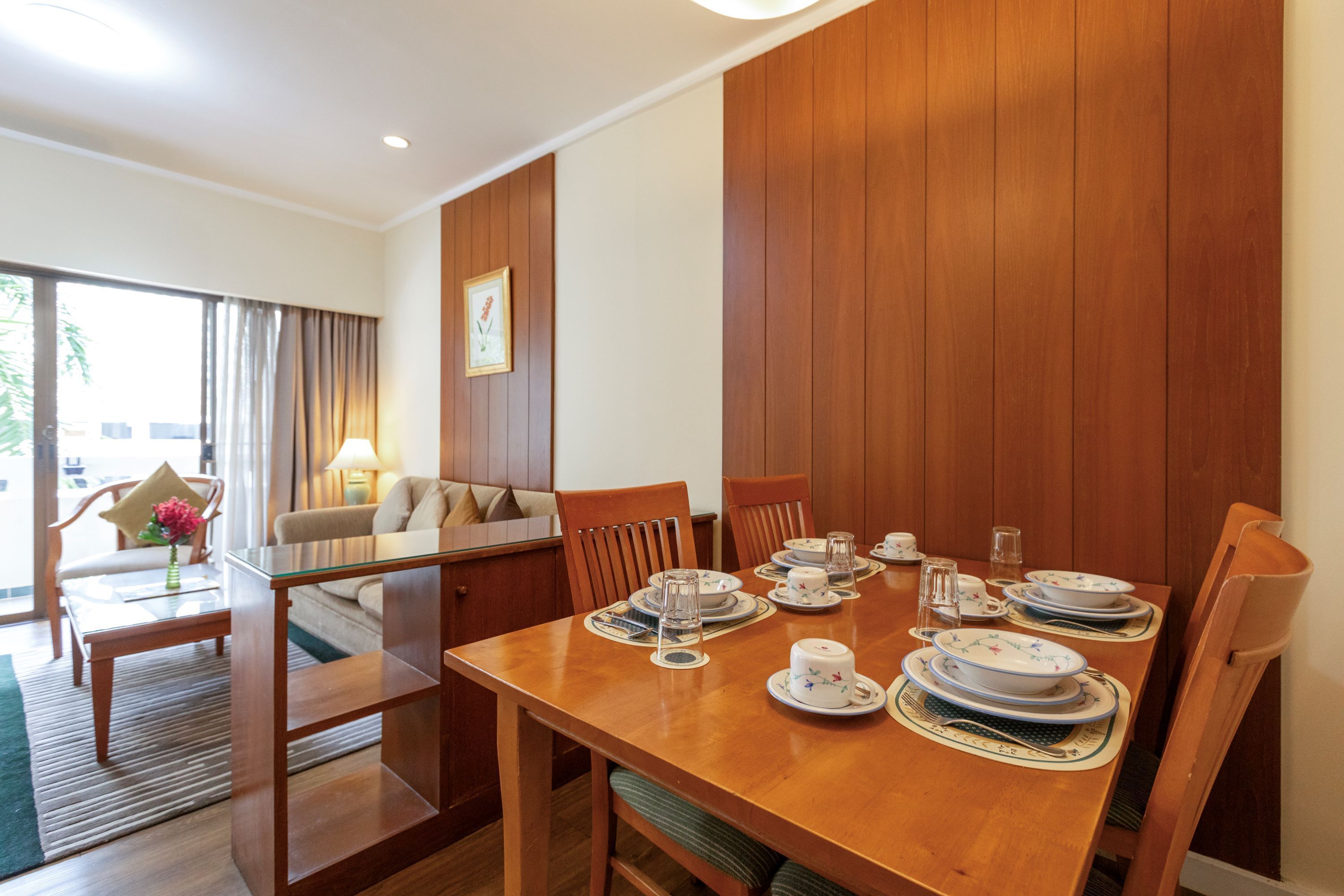 Comedor con mesa de madera dispuesta para cuatro personas, rodeado de sillas.
