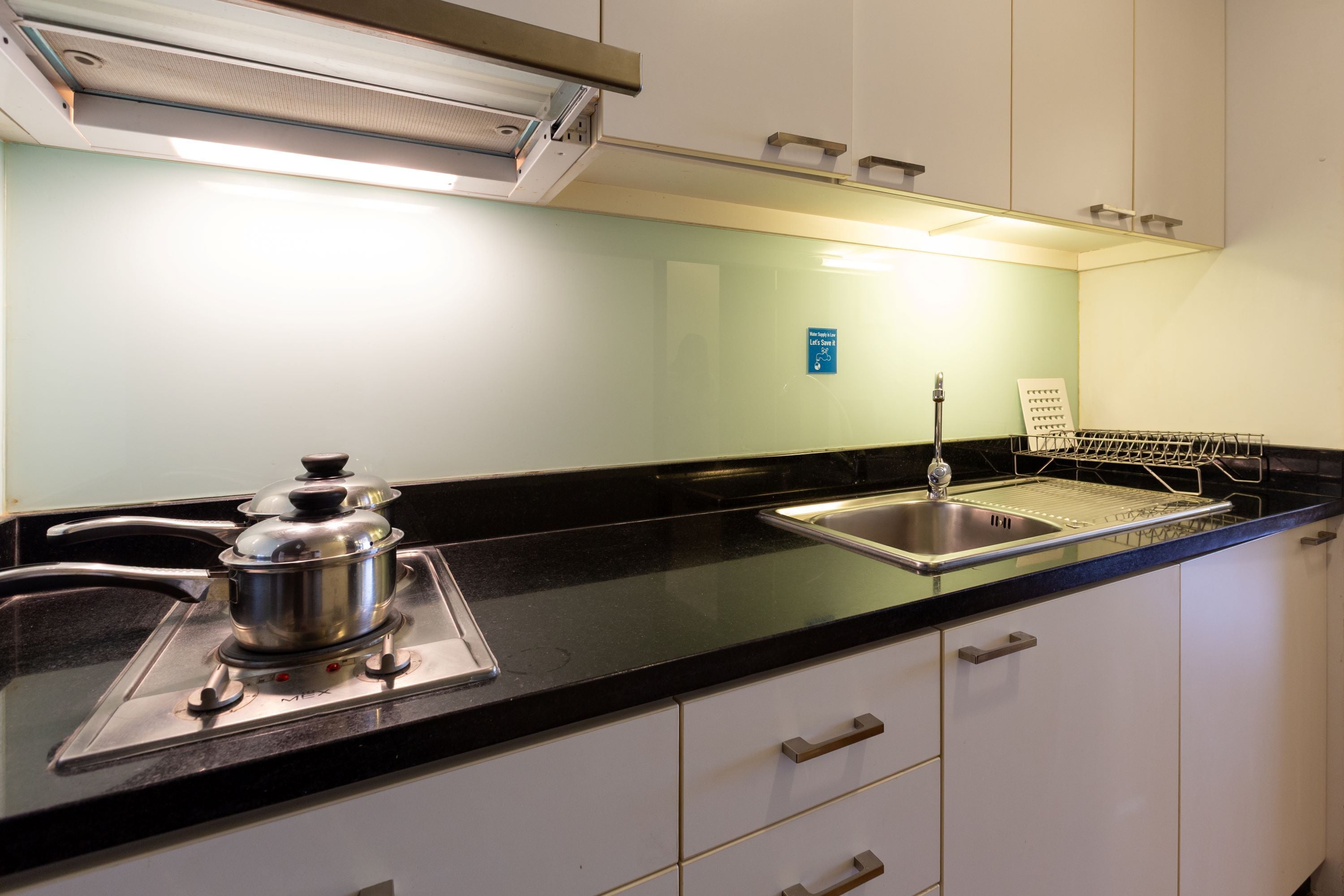 A kitchen with a stove, sink, and a dish rack.