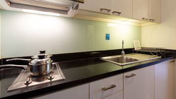 A kitchen with a stove, sink, and a dish rack.