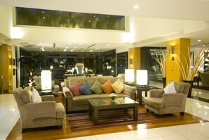 A modern lobby with a high ceiling, a glass wall, and a seating area with a sofa and armchairs. - Kantary House Hotel & Serviced Apartments (Bangkok)