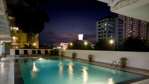 Piscina interior con agua cristalina, rodeada de sillones de descanso y plantas en macetas.