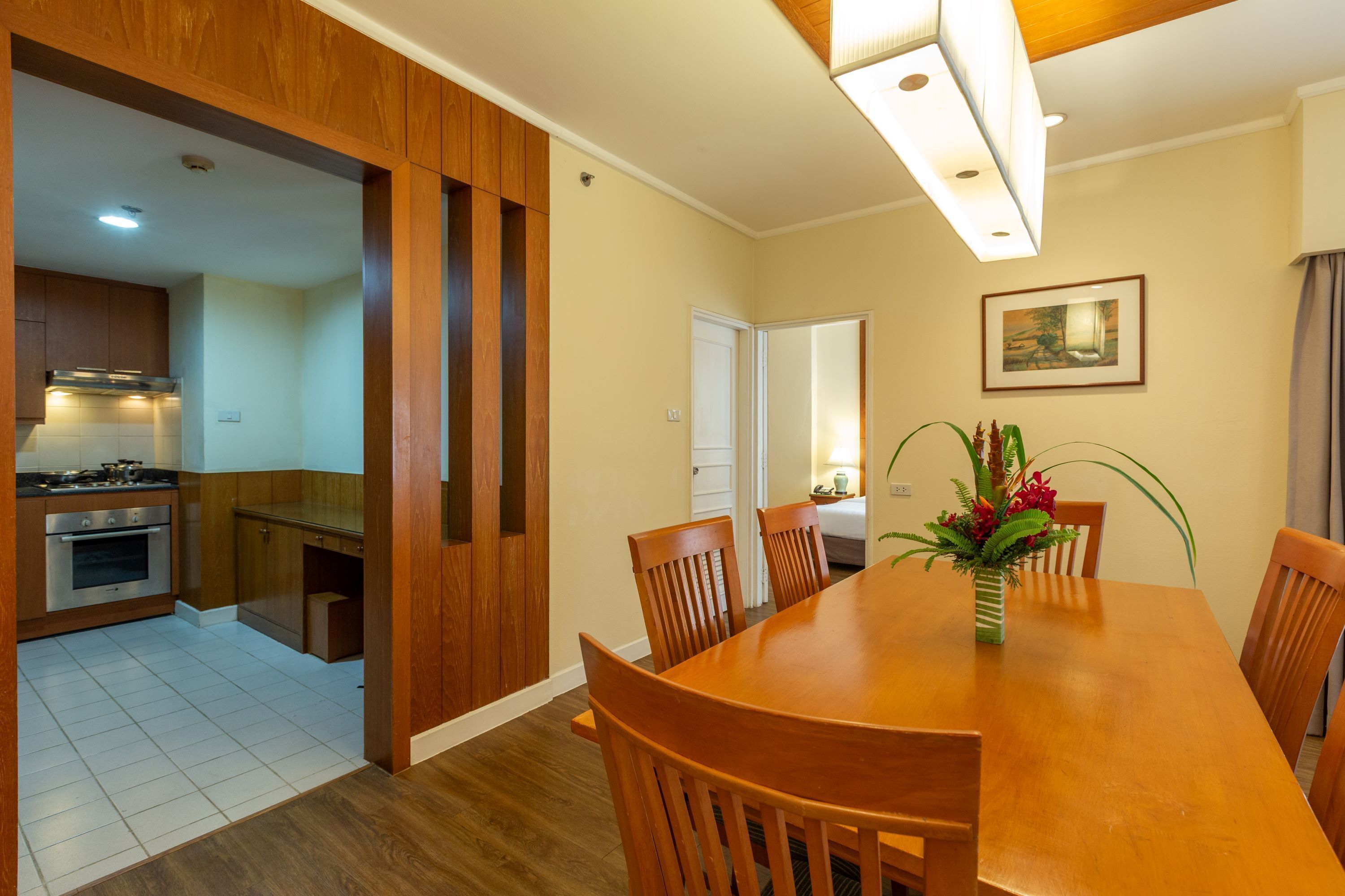 Un coin repas avec une table et des chaises en bois, un vase rempli de fleurs et un tableau accroché au mur.