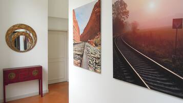 Una habitación con una mesa consola de madera, un espejo redondo y dos cuadros en la pared.