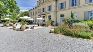 A large building with a courtyard, outdoor seating, and potted plants. - Hotel Estelou (Sommieres)