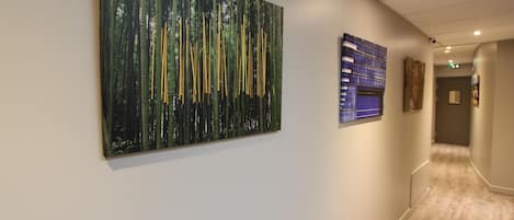 A hallway with a large abstract painting on the left and a blue patterned artwork on the right.