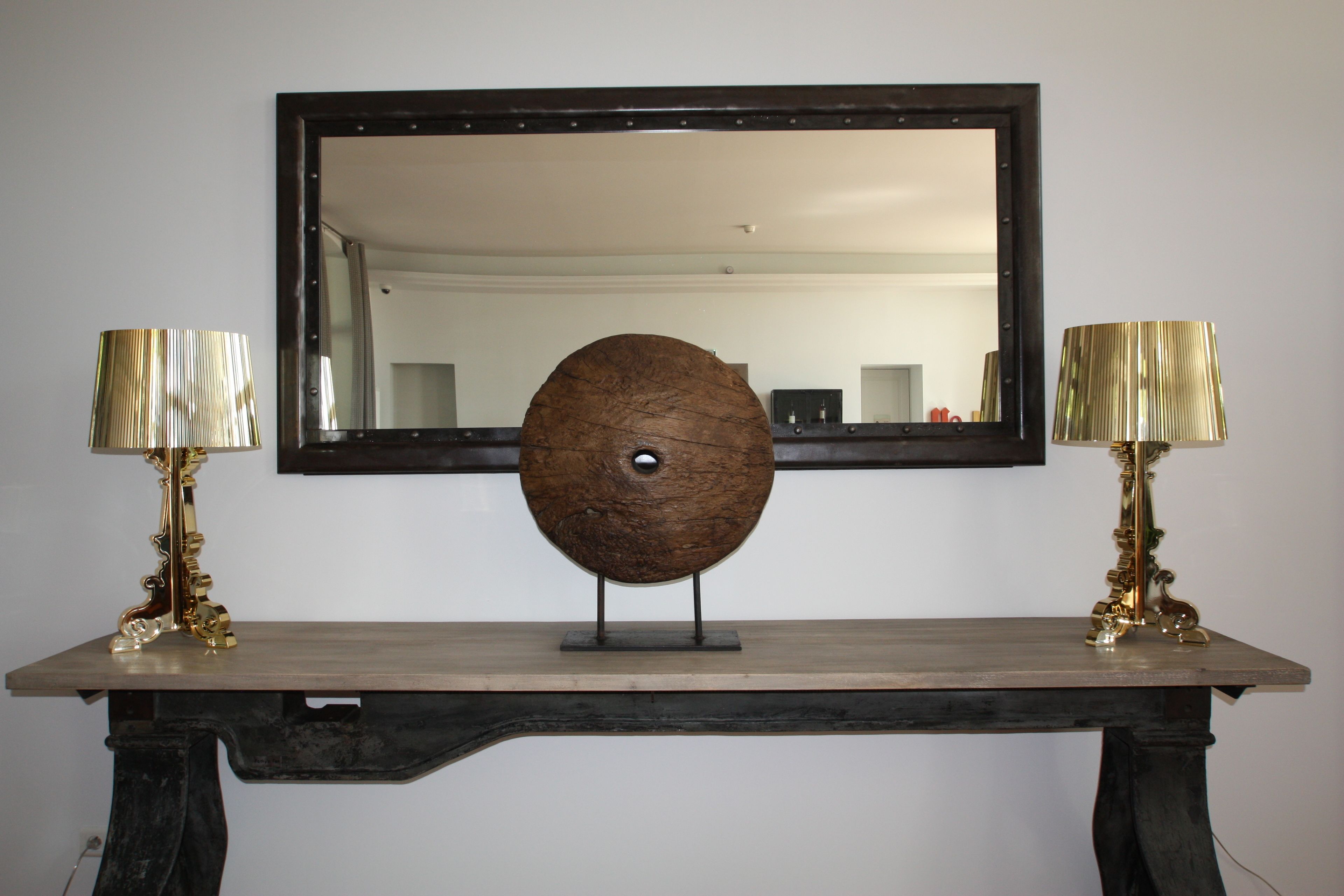 A wooden console table with two lamps on either side and a large mirror above.