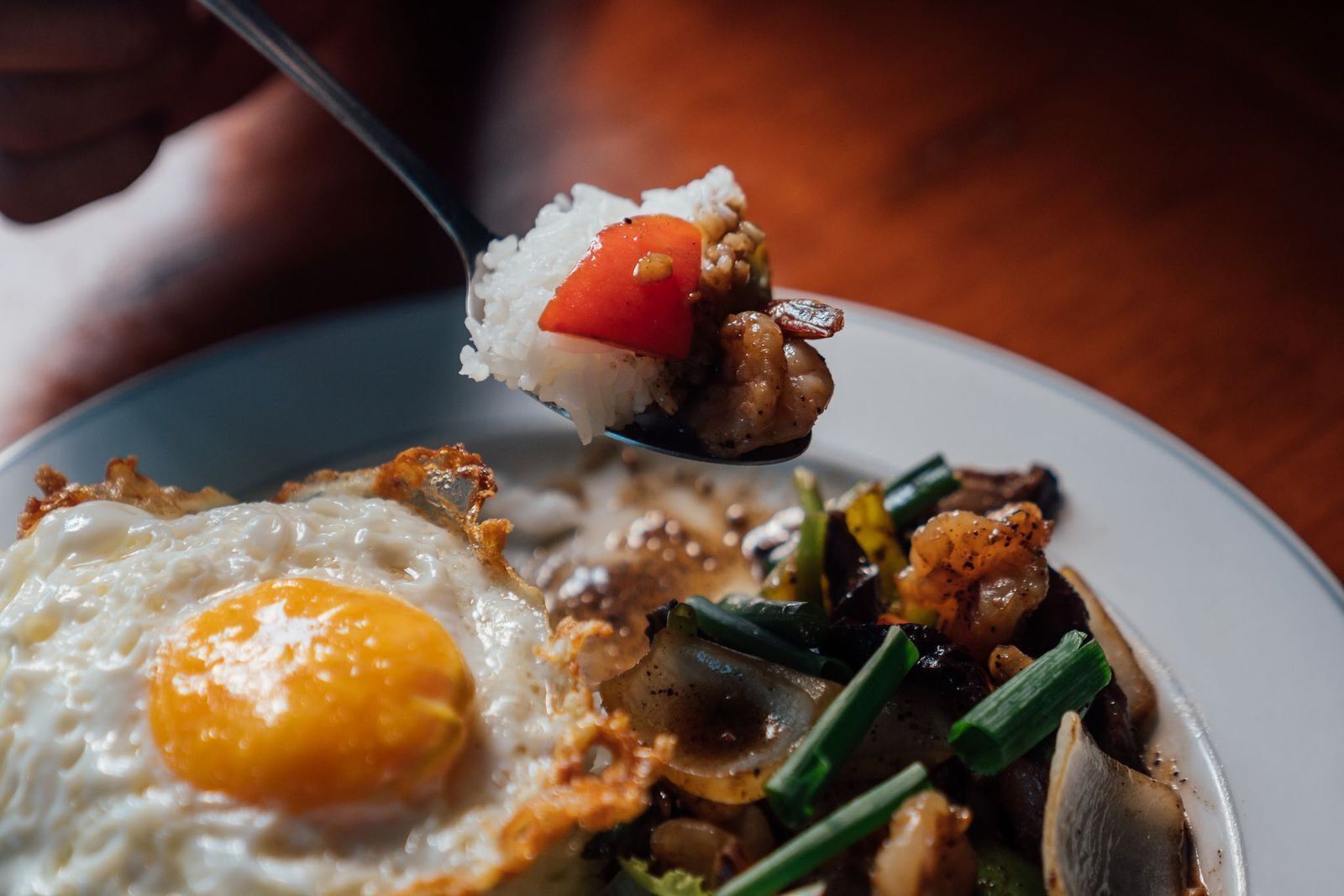 A close-up of a dish with fried egg, vegetables, and rice.