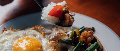 A close-up of a dish with fried egg, vegetables, and rice.