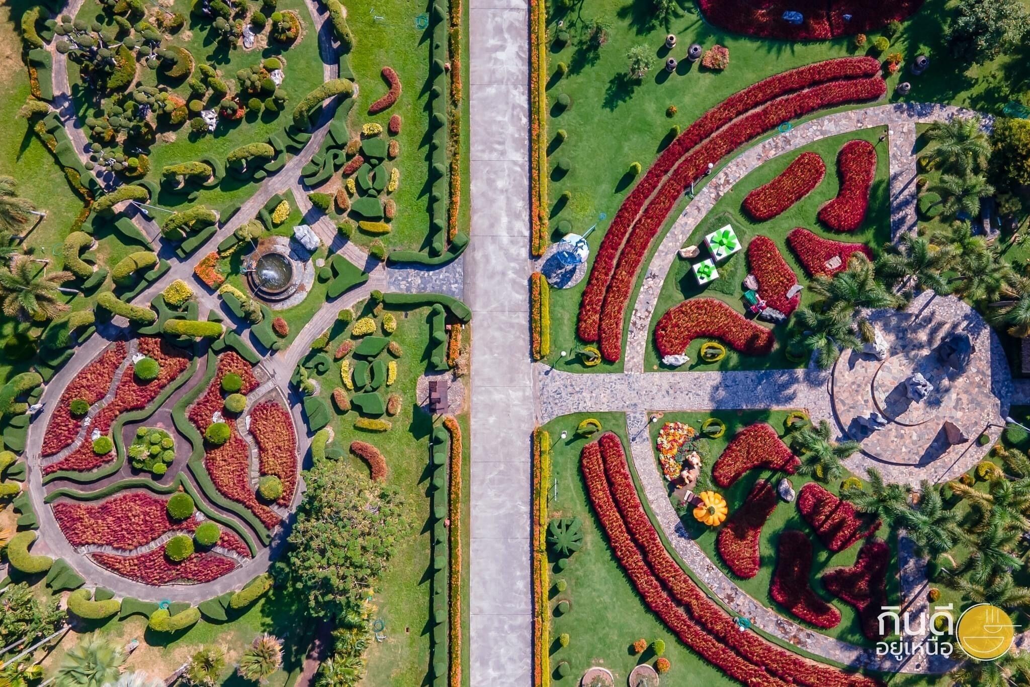 An aerial view of a landscaped garden with geometric flower beds, pathways, and a central fountain.