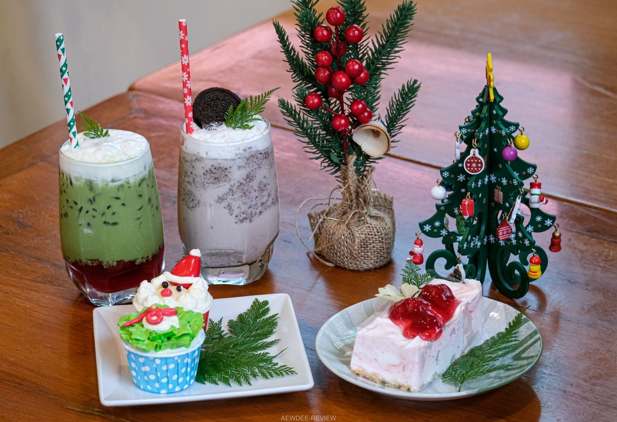 Une table avec deux boissons, un petit sapin de Noël et un cupcake.