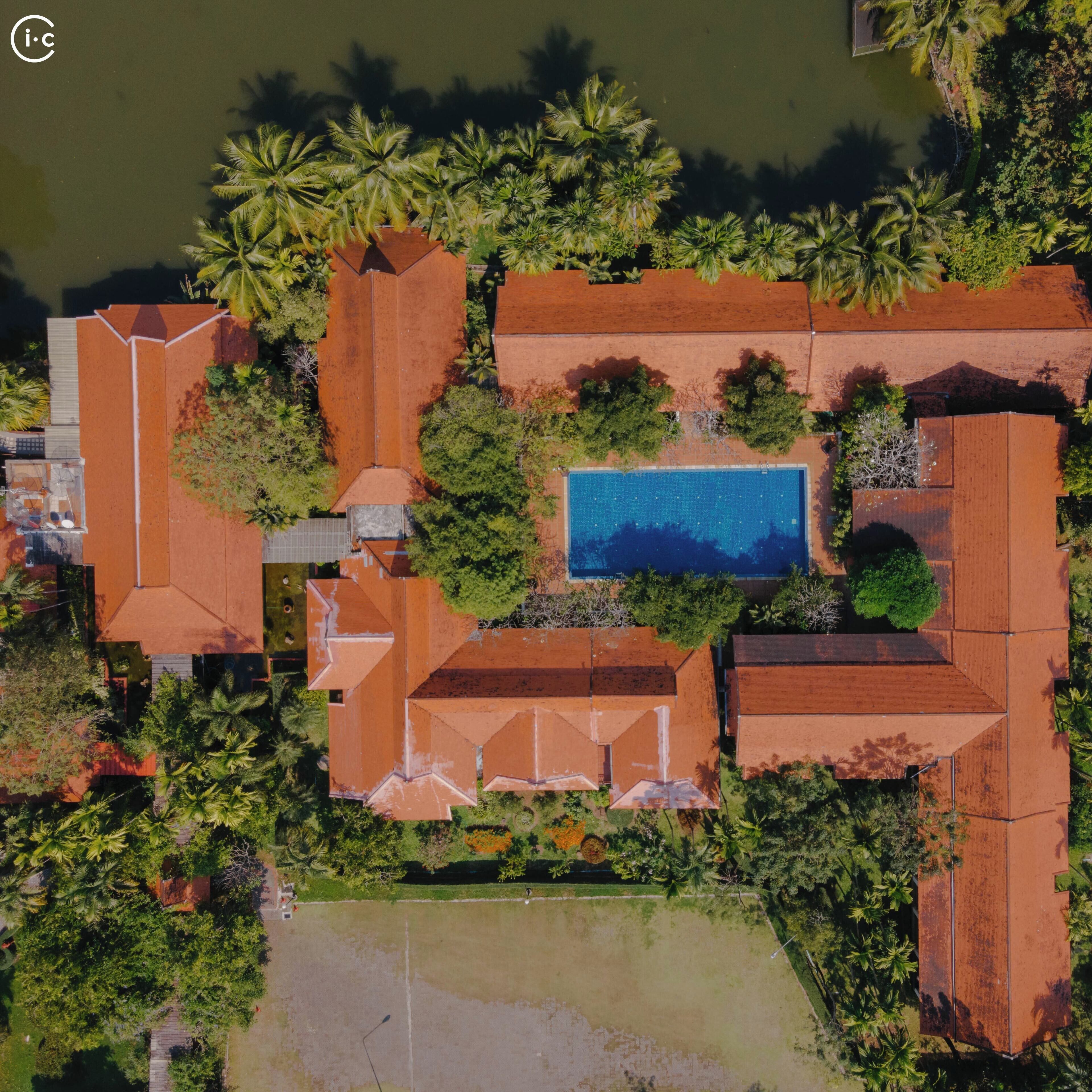 Vista aérea de un resort con varias edificaciones, una piscina y abundante vegetación.