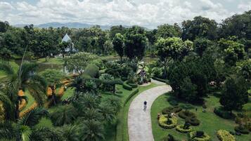 Un jardín exuberante con un sendero serpenteante, un mirador y un estanque pequeño.
