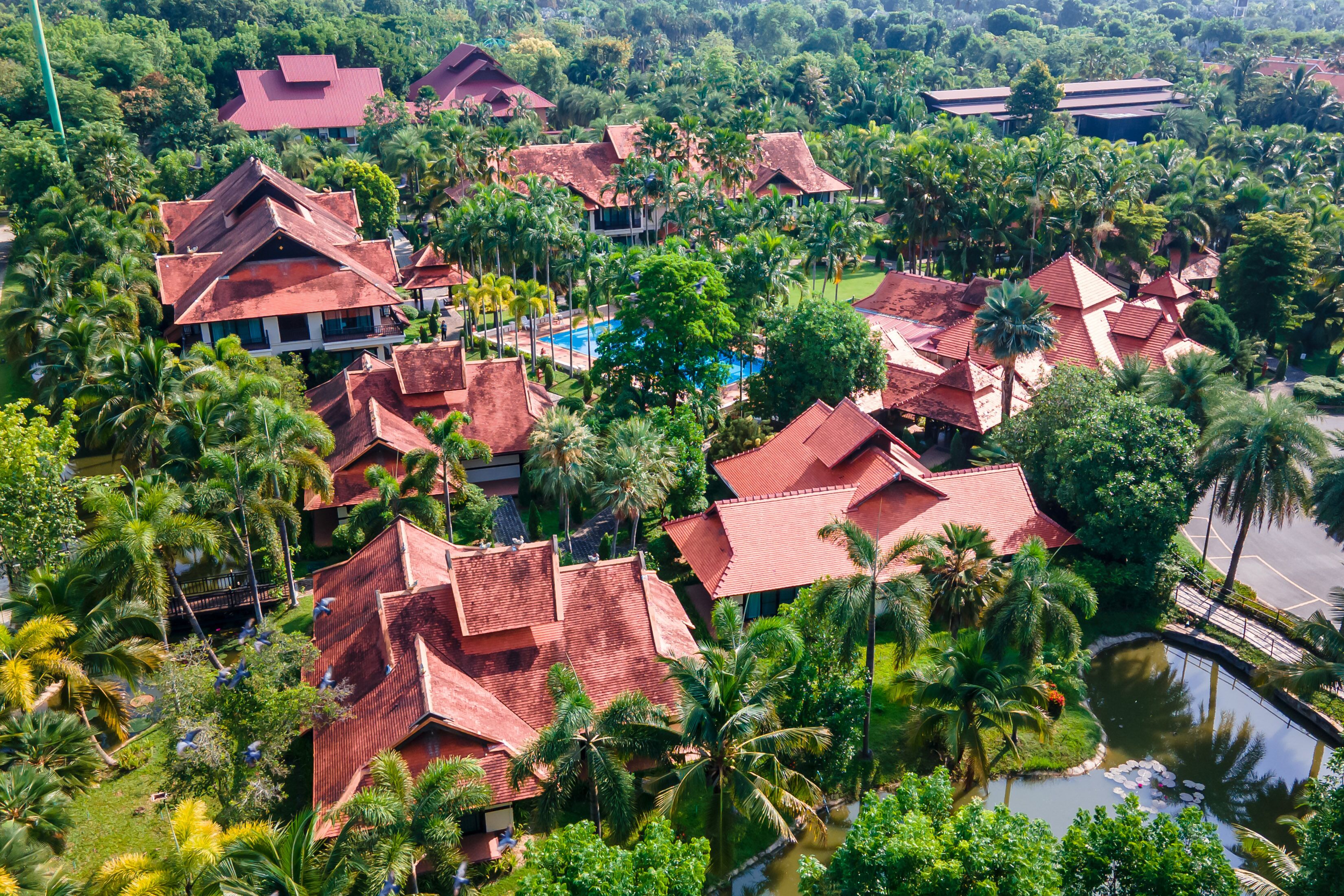 An aerial view of a resort with multiple buildings, palm trees, and a swimming pool.