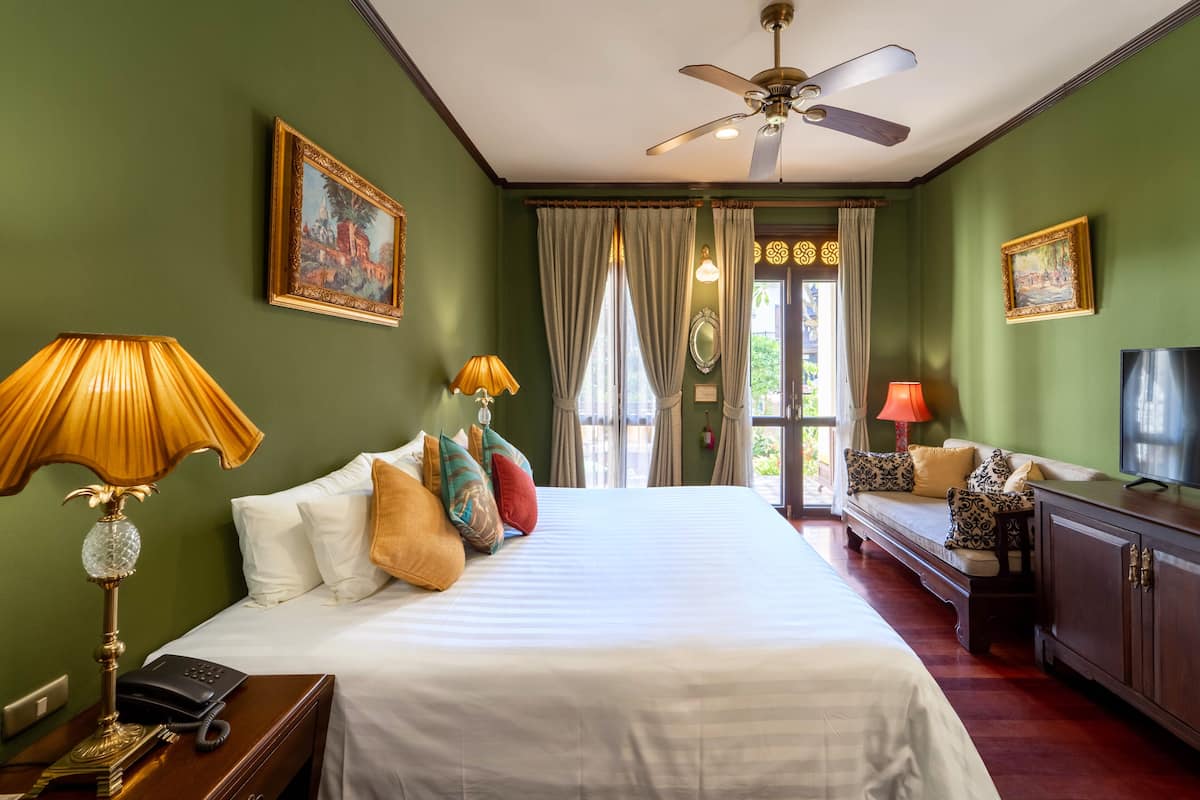 Ein Hotelzimmer mit einem großen Bett, zwei Nachttischlampen, einem Deckenventilator und einem Fernseher.