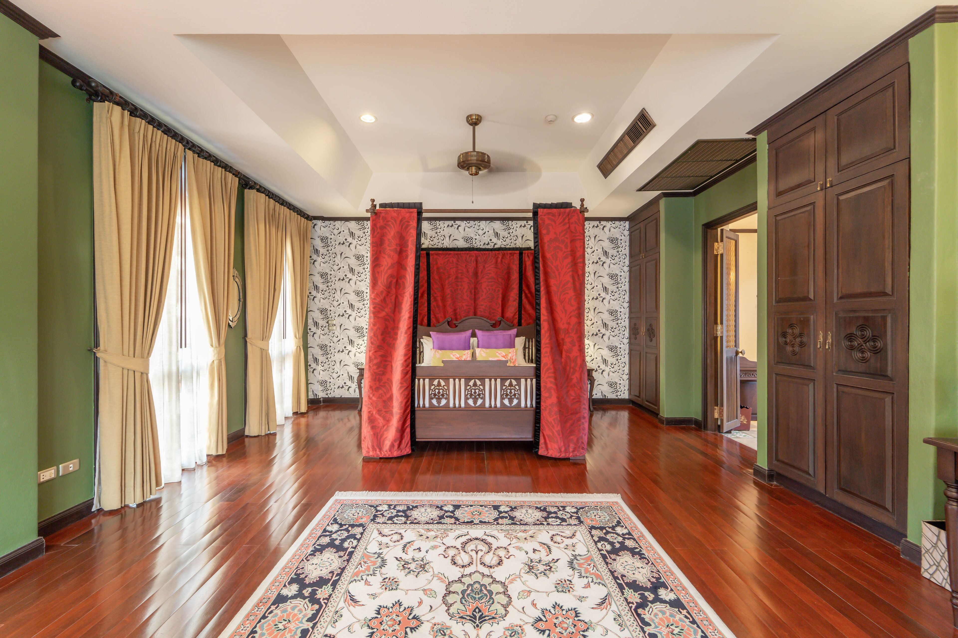 A bedroom with a large bed, a ceiling fan, and a patterned rug.