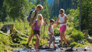 A family crossing a shallow stream in a forested area.
