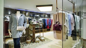 A clothing store with a mannequin, racks of clothes, and a display of shoes.