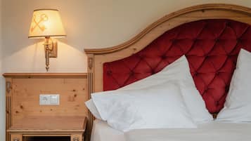 A neatly made bed with white linens and a red tufted headboard.