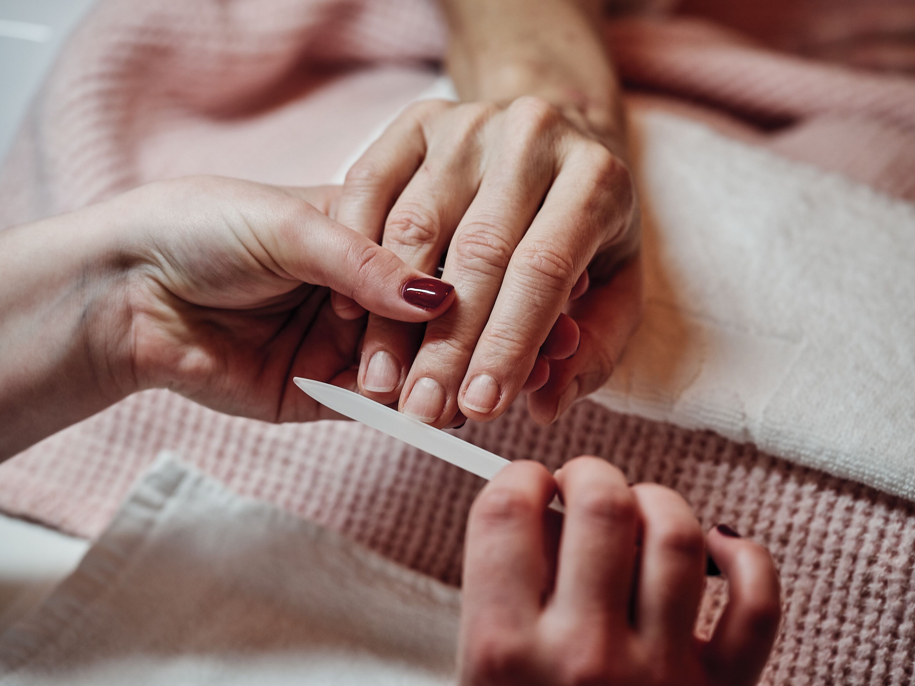 A close-up of hands receiving a manicure.