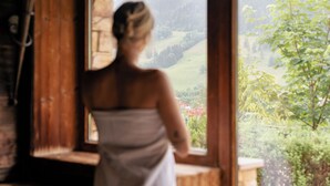 Una persona de pie junto a una ventana con vistas a un paisaje verde.